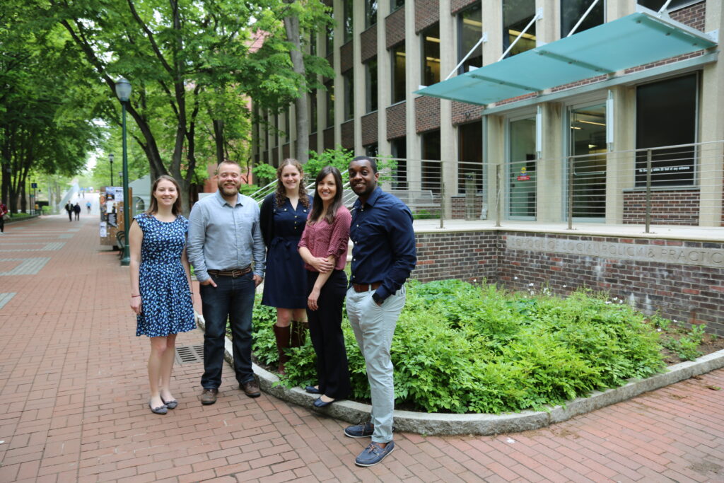 Five students stand outside of the Caster building