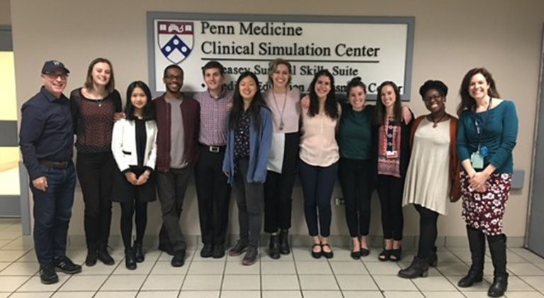 Zvi Gellis and study participants pose smiling before a sign that says "Penn Medicine Clinical Simulation Center"