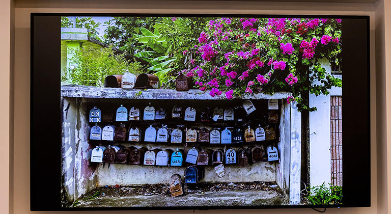 A photo of mailboxes and flowers appears on a digital screen in the lobby.