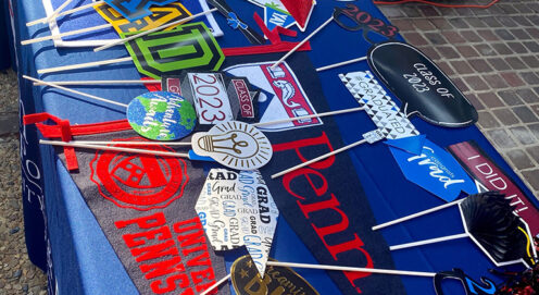 Red and blue branded Penn pennants and celebratory graduation items are arranged on a table