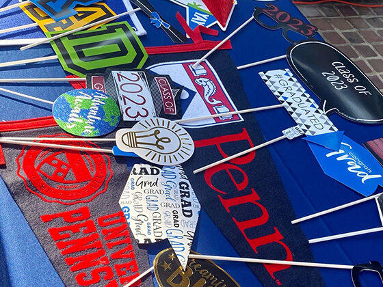 Red and blue branded Penn pennants and celebratory graduation items are arranged on a table